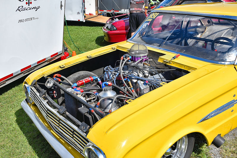 Close-up of a yellow race car's engine compartment showcasing a detailed engine setup with various colored hoses and components.