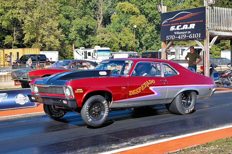 A red and silver drag racing car named 'Desperado' on a racetrack, with spectators and a timing tower in the background.