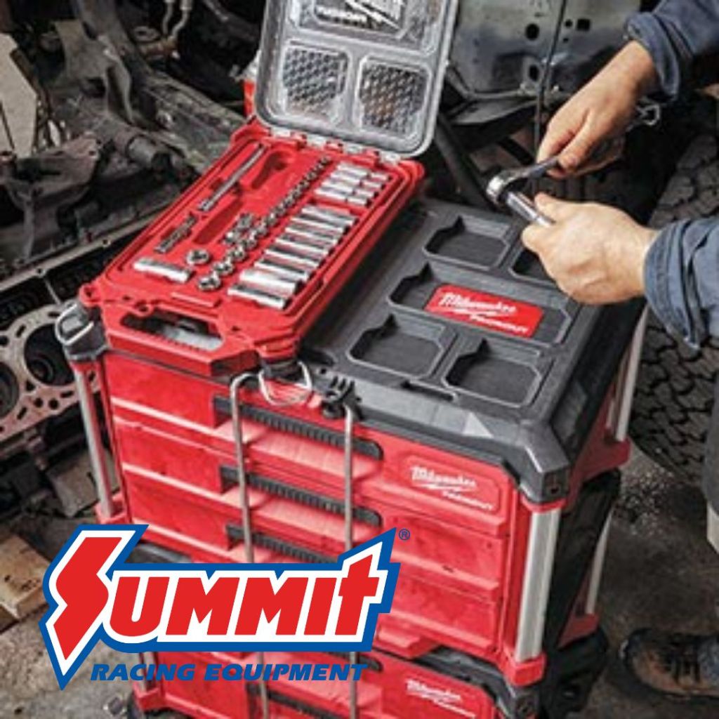A person using a ratchet tool from a red and black tool storage system, featuring an open top compartment with various sockets and a sturdy base, placed near a vehicle engine.