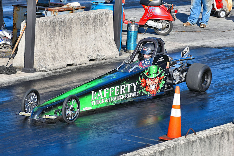 A colorful drag racing car with 'Lafferty Truck & Trailer Repair' branding, positioned on a racing strip with a traffic cone in the foreground.